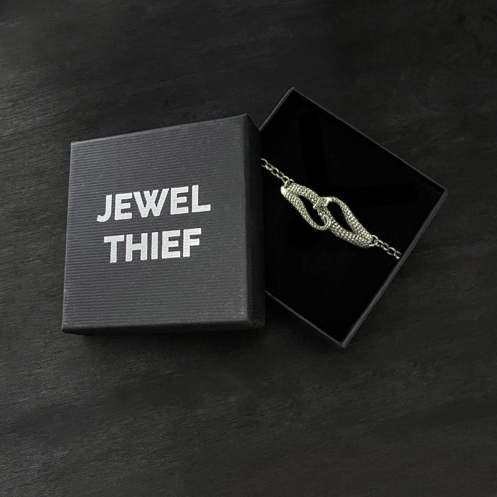 Bracelet in a 'Jewel Thief' branded box on a dark surface